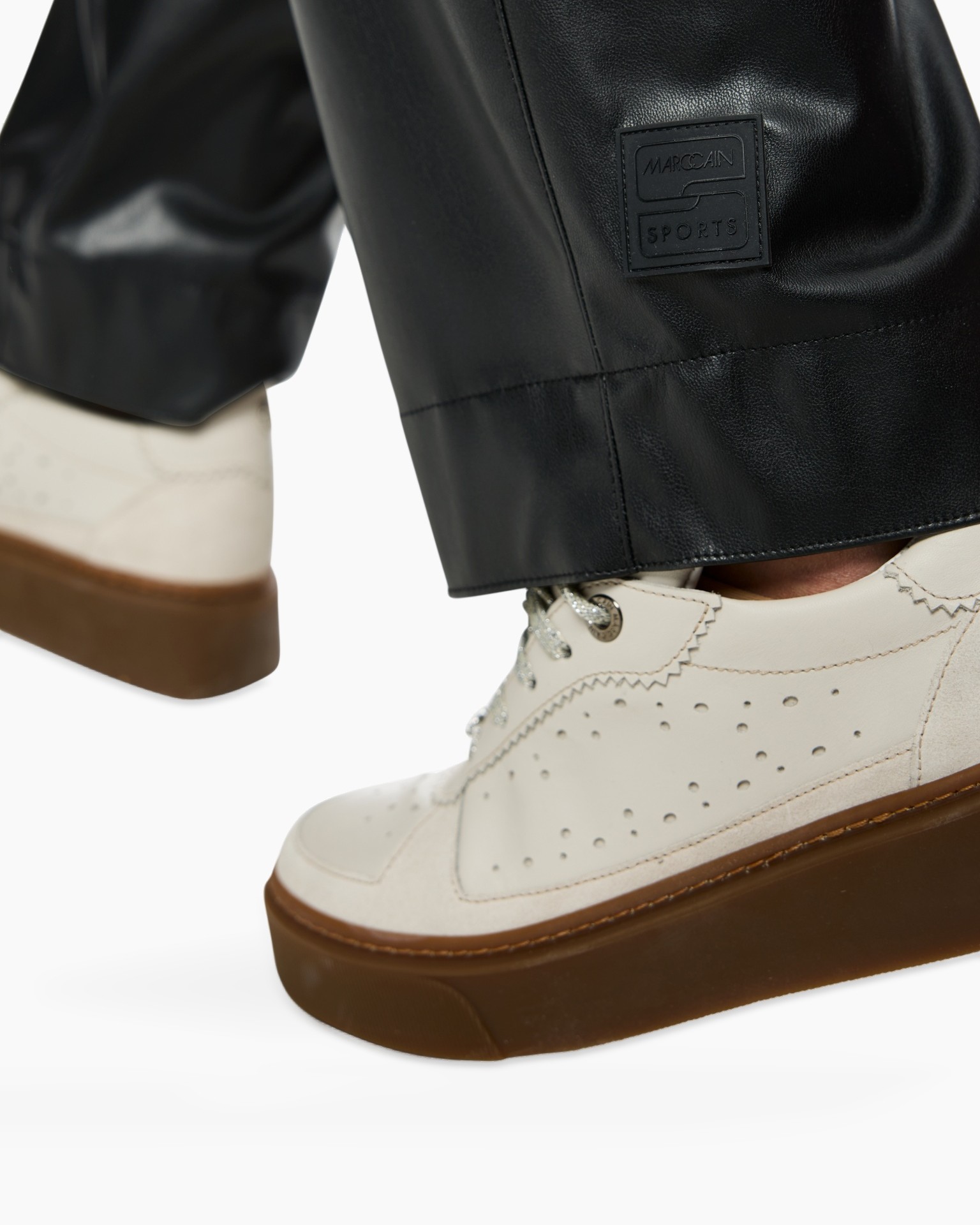leren broek, zwarte broek, label patch?, merk label op zoom, witte sneaker, gaten patroon