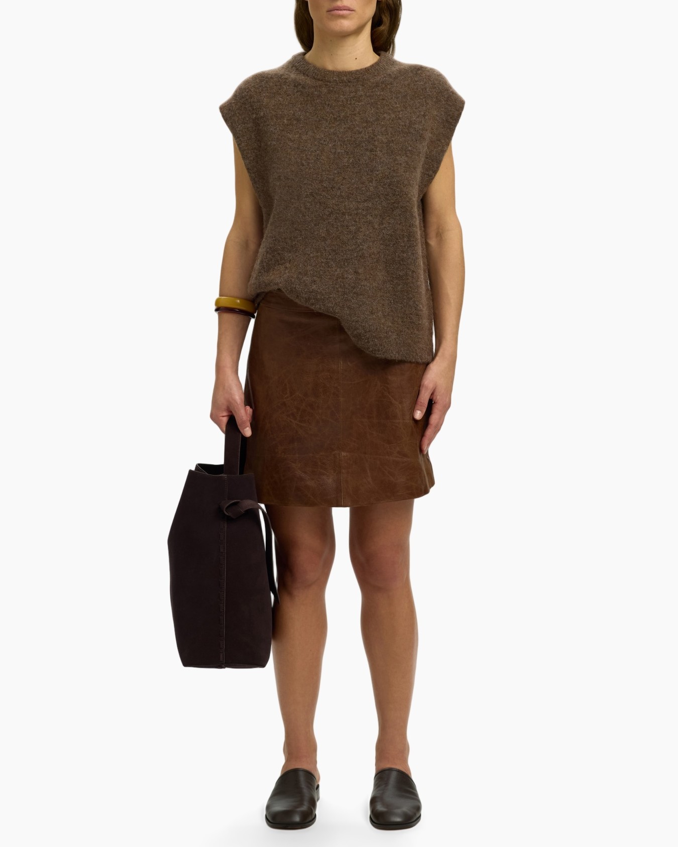 tunikaslank, bruin shirt, gebreide mouwloos, asymmetrische zoom, bruine leren rok, handtas, loafers, armbands, aardetonen