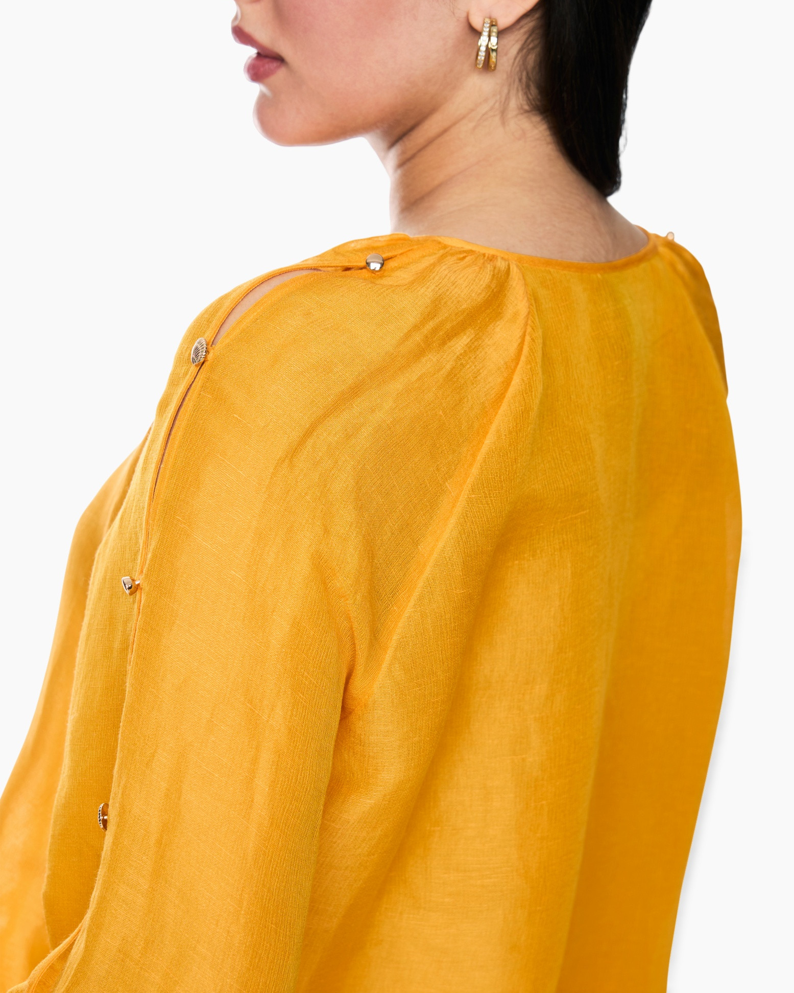 geel shirt, linnen stof, schouder detail, knopsluiting, gouden sieraden (niet op het kledingstuk)