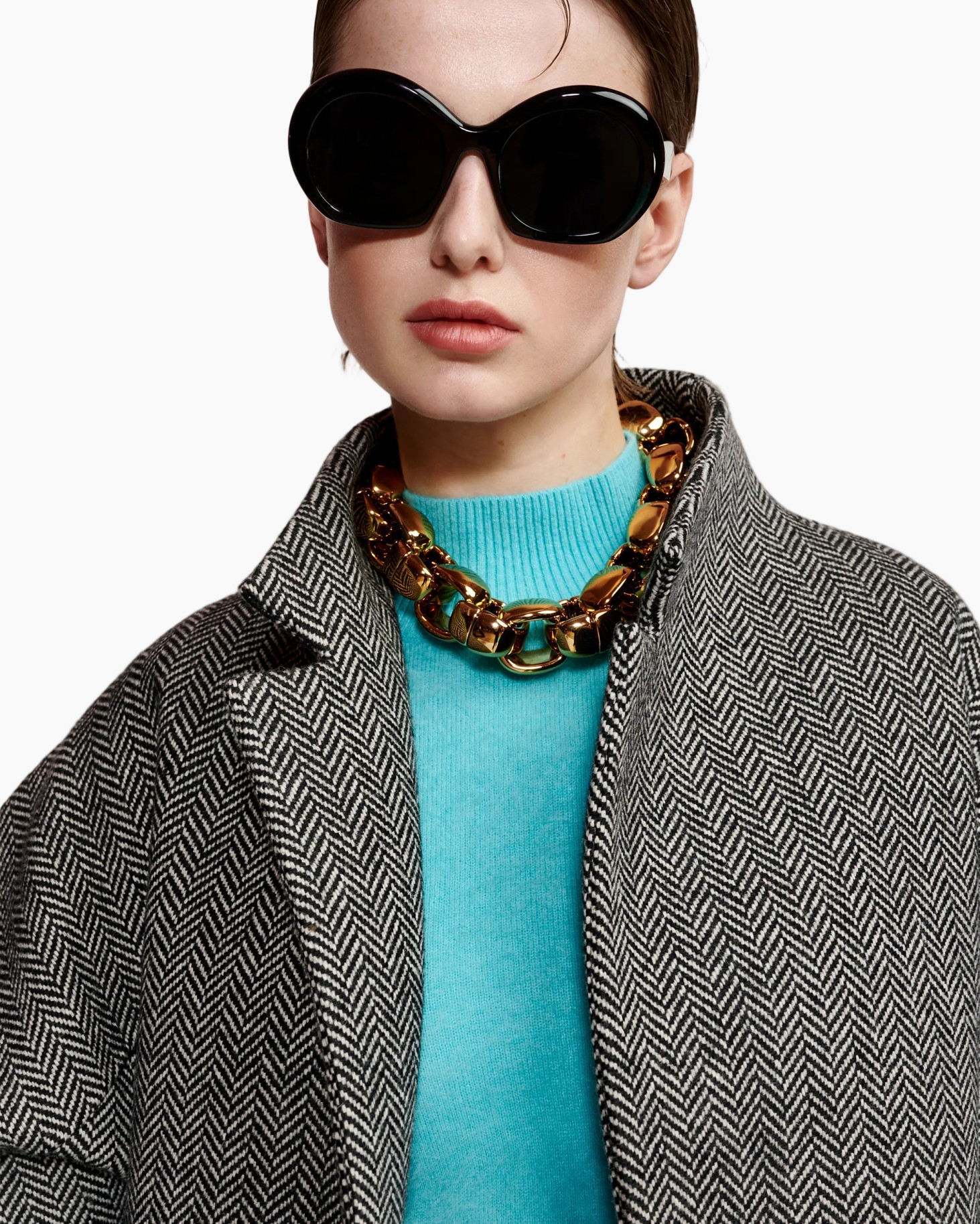 zonnebril, dikke ketting, herringbone jas, turquoise trui, mode-accessoire