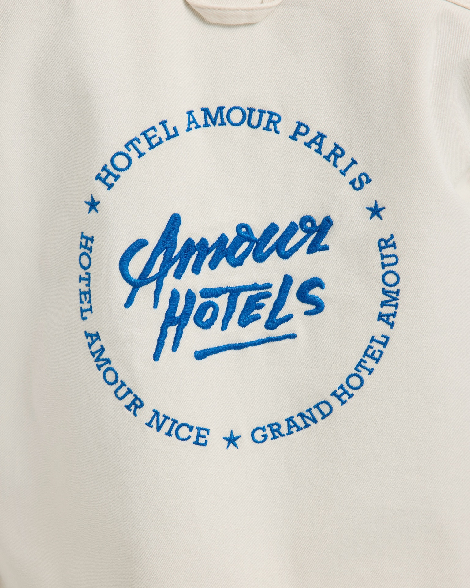 grafische tee, ronde afbeelding, blauwe tekst, witte stof, hotelmotief