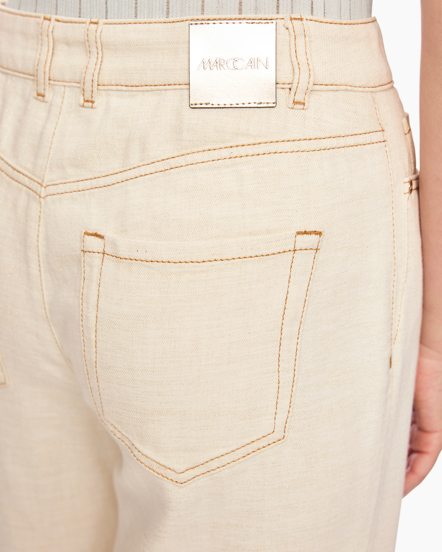 beige broek, achterzak, naaldstiksels, riemlus, metaallogo